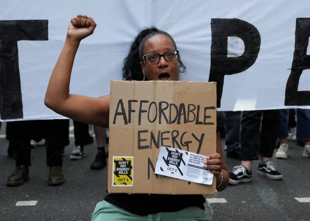 Ein britischer Demonstrant haelt ein Banner fuer bezahlbare Energie hoch 1